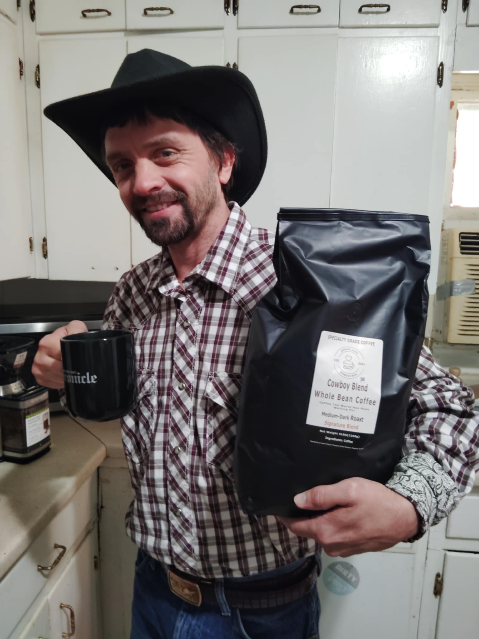 Man wearing a cowboy hat holding a 5-pound bag of Jones’N Java Cowboy Blend coffee in a kitchen