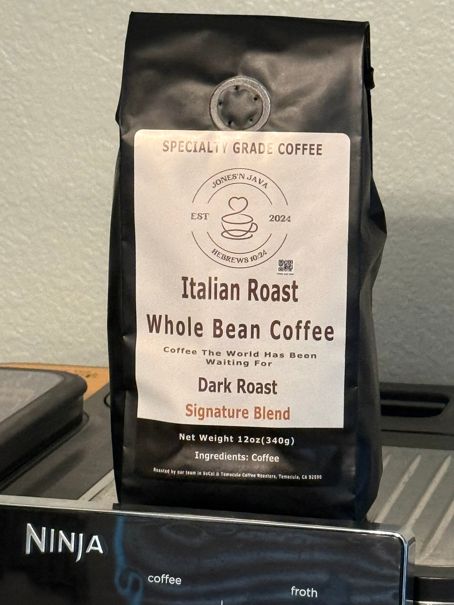 Italian Roast whole bean coffee by Jones’N Java on a kitchen counter with a coffee machine in the background.