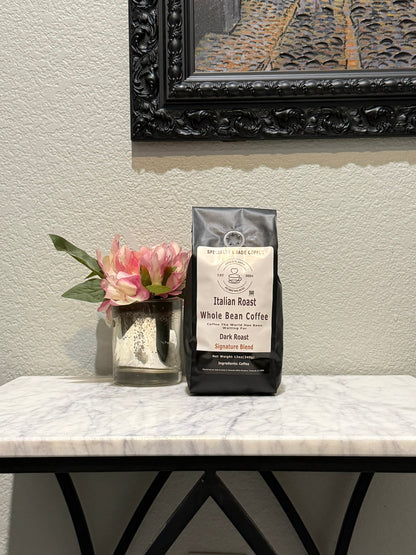 Italian Roast whole bean coffee by Jones’N Java on a marble table with flowers and framed artwork in the background